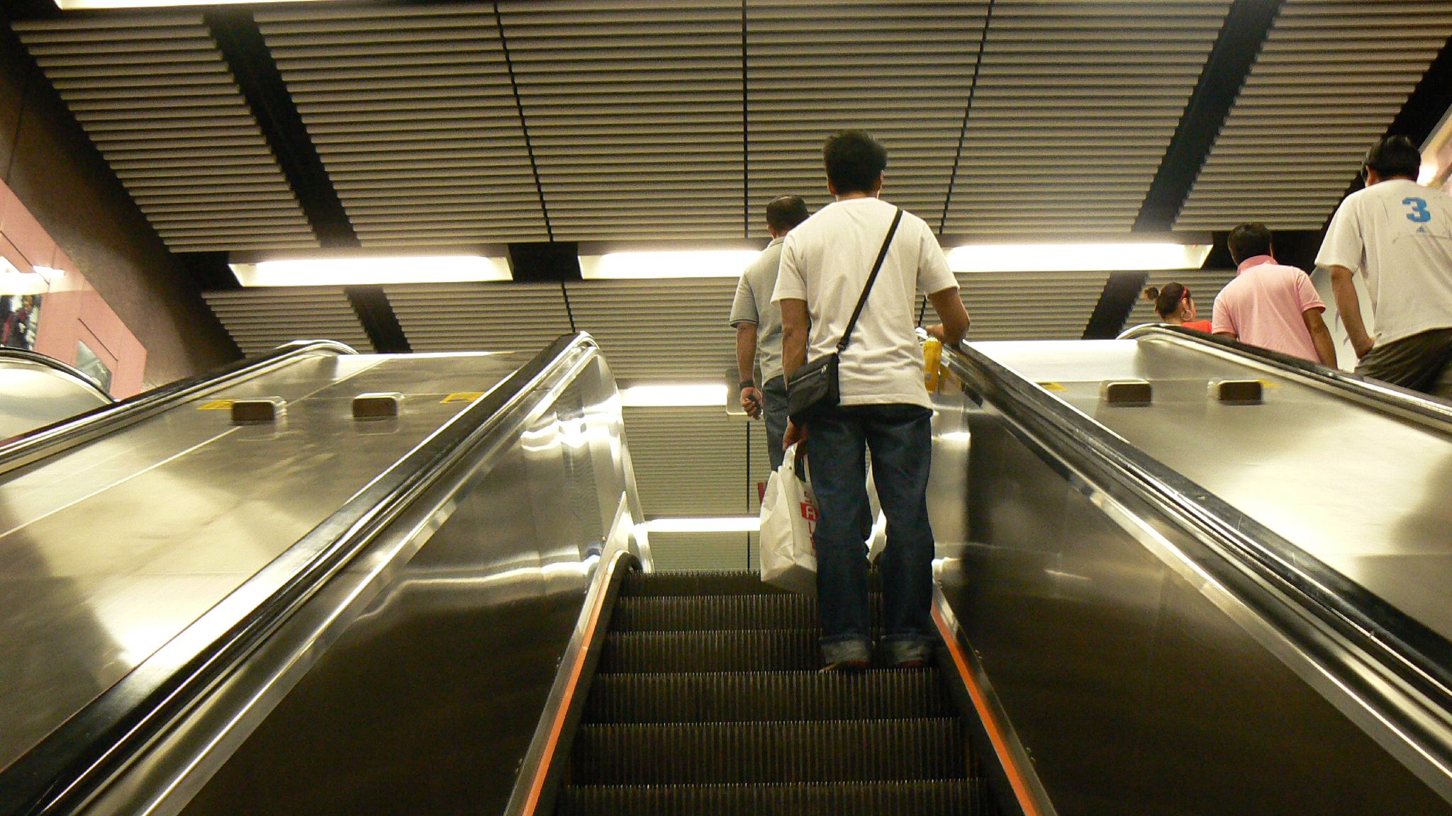 a man walks down an escalator as others walk by