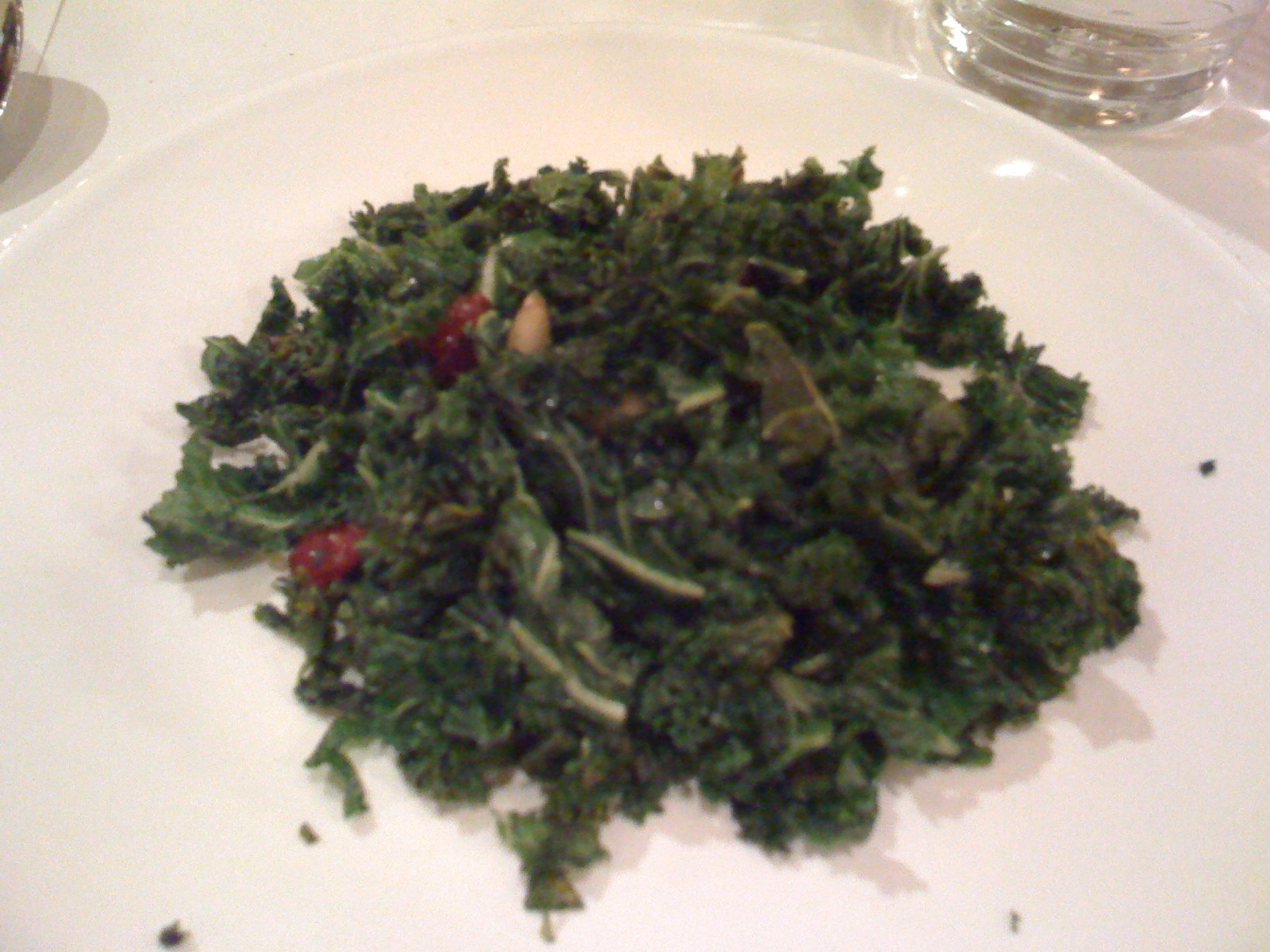 a plate with green food on it and wine glasses around it