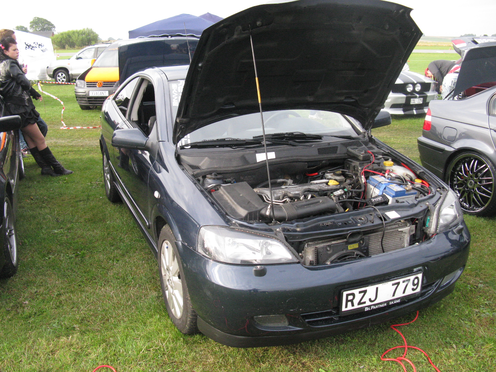 two men looking at the hood of a small car