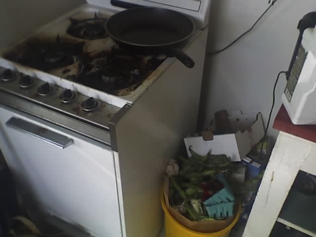 a messy kitchen and a stove with a pot on top