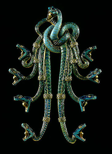 an ornately designed snake brooch is set in metal