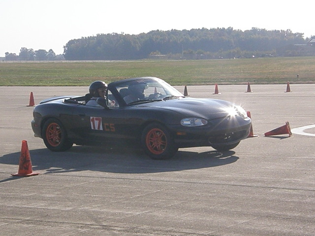 a person in a convertible car sitting next to cones