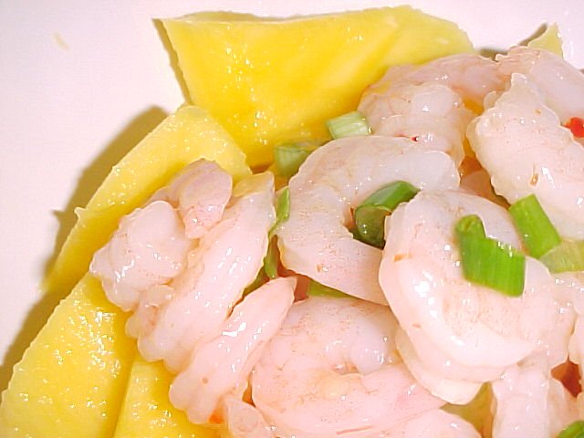 shrimp and pineapple are in a plate with a wedge of cheese