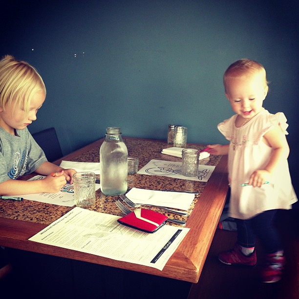 two children sitting at a table using a calculator