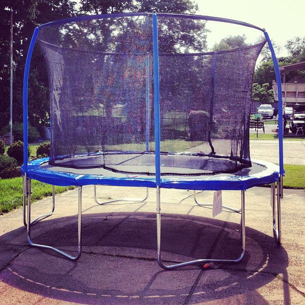 a blue trampoline with a net and two poles