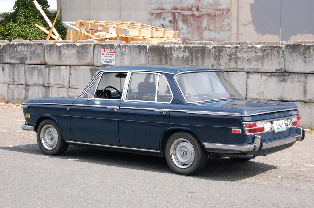 an old blue car parked on the side of a road