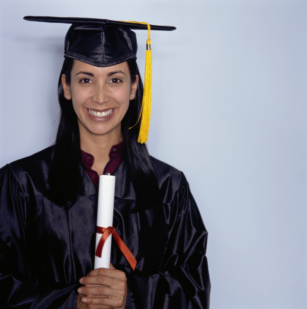 a smiling female graduate holds her cap and diploma