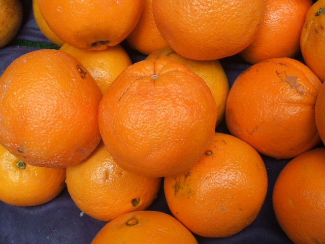 some oranges with leaves and one with a yellow in it