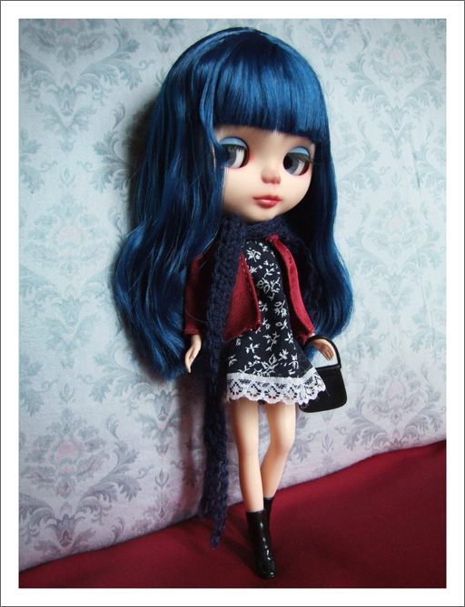 a doll with blue hair standing in front of wallpaper