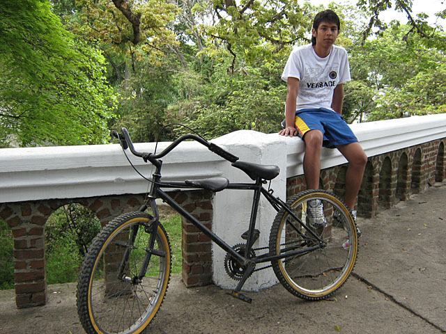 young man sitting on a white bench with a bicycle