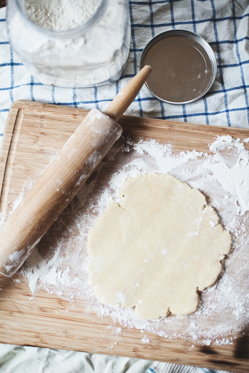 a wooden plate holding dough next to a rolling pin