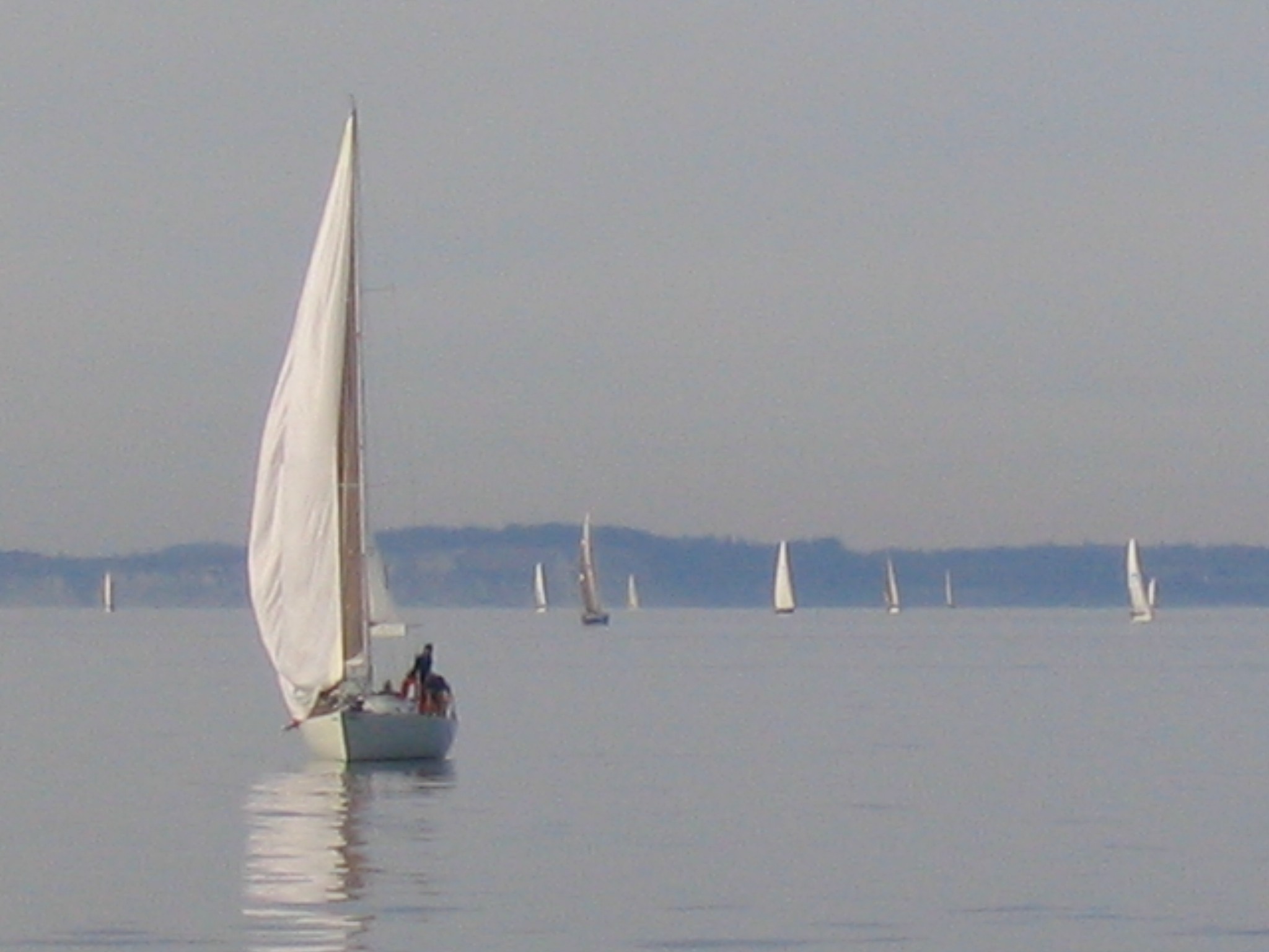 two people riding on the back of a sailboat in a large body of water