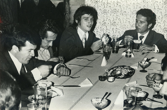 a group of men sit around a table drinking