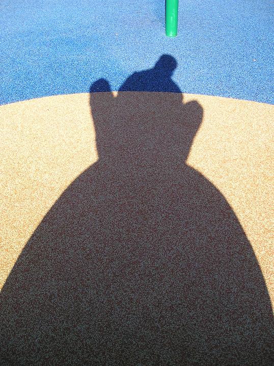 shadow from a park bench with a person casting a large shadow