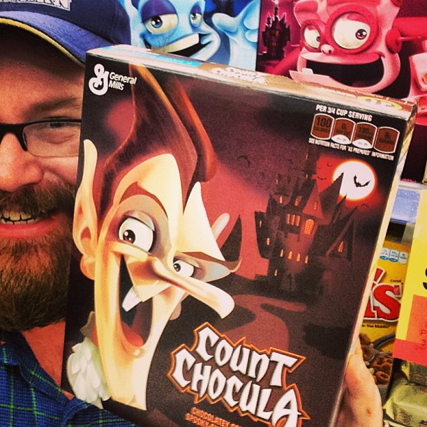 a man holding up a box of chocolate in front of halloween decorations