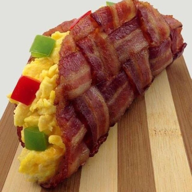 a wooden  board topped with bacon, eggs and cheese