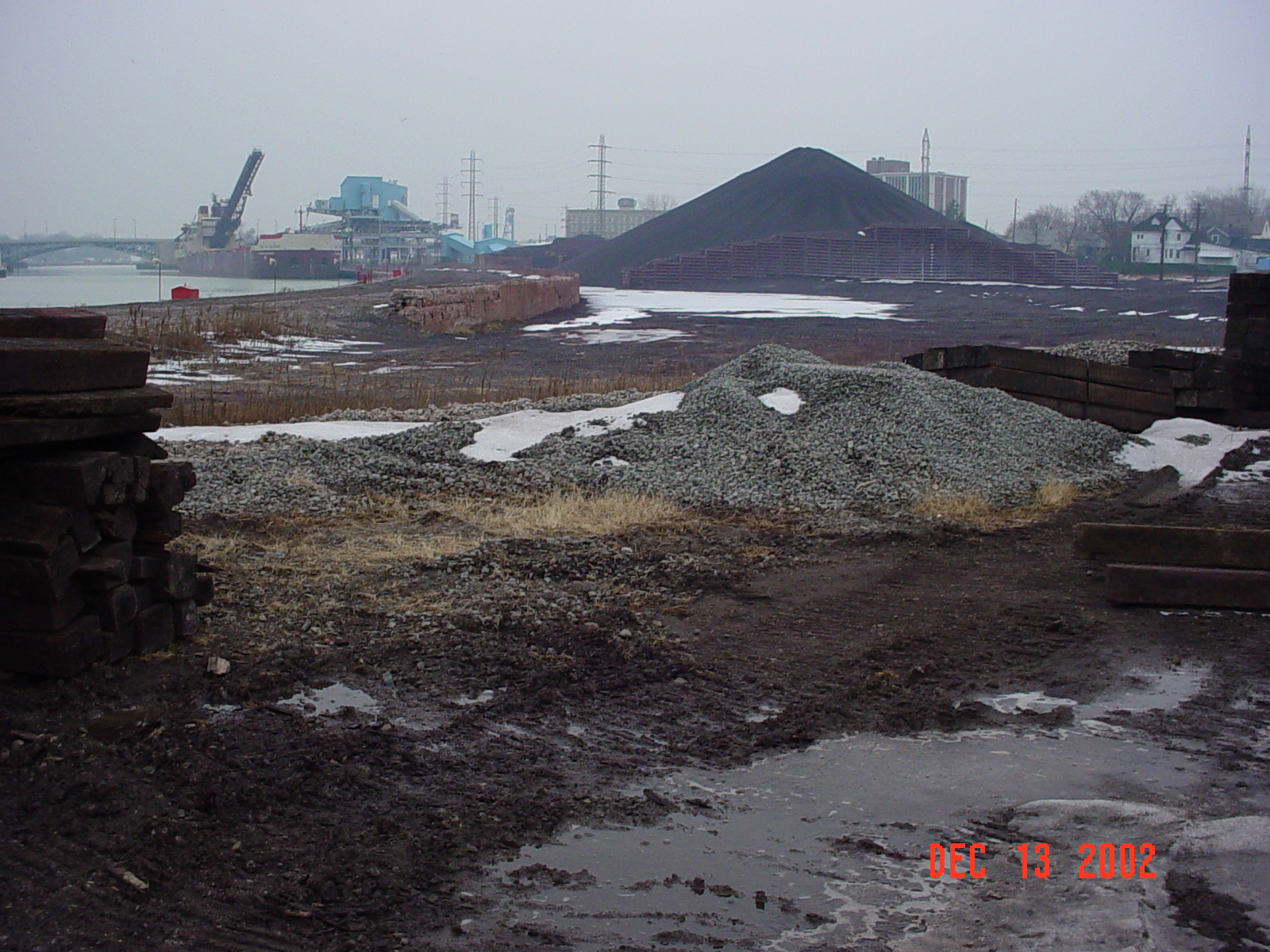 a pile of black sand sitting next to a forest