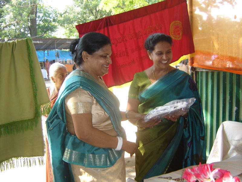 two women are talking in front of a food stand