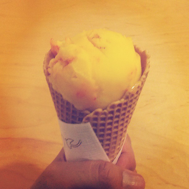 someone holding a ice cream with pink and yellow sprinkles