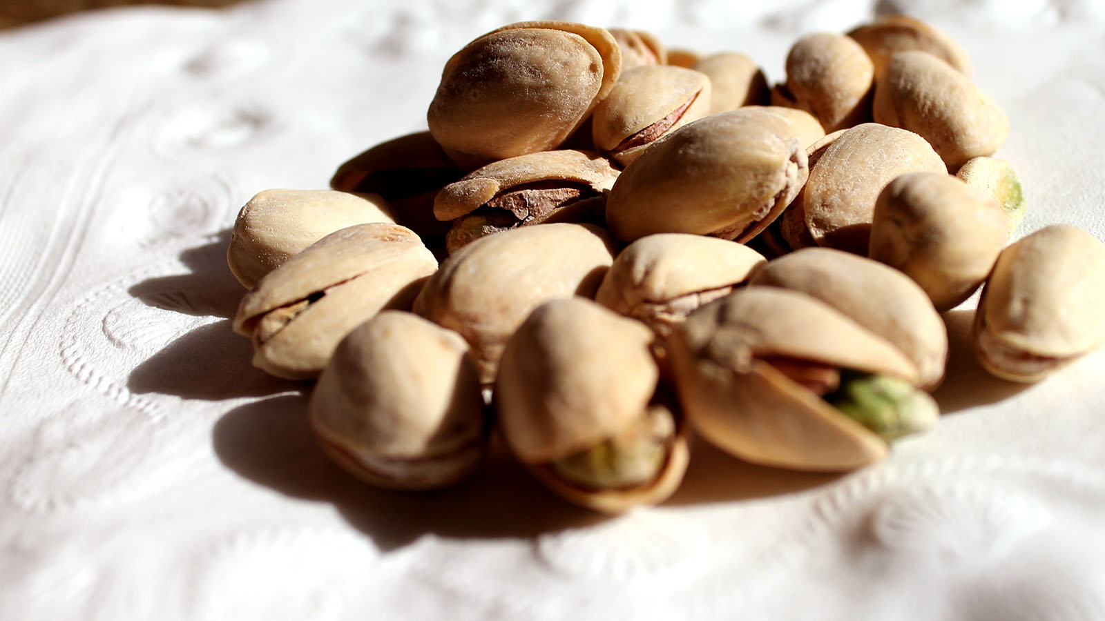 pistachio nuts on a cloth that is white