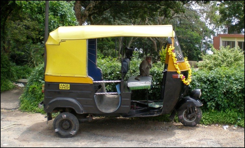 a yellow and black three wheeled motorcycle parked in front of some trees