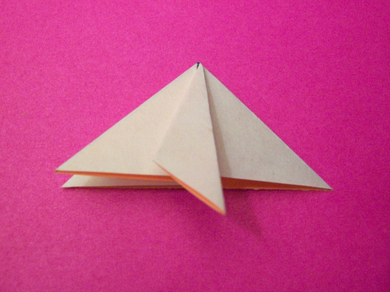 a paper airplane on top of a pink surface