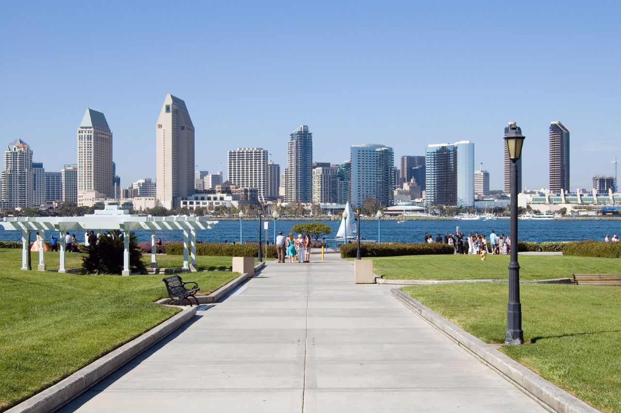 a walkway leads to an urban park and a river in the background