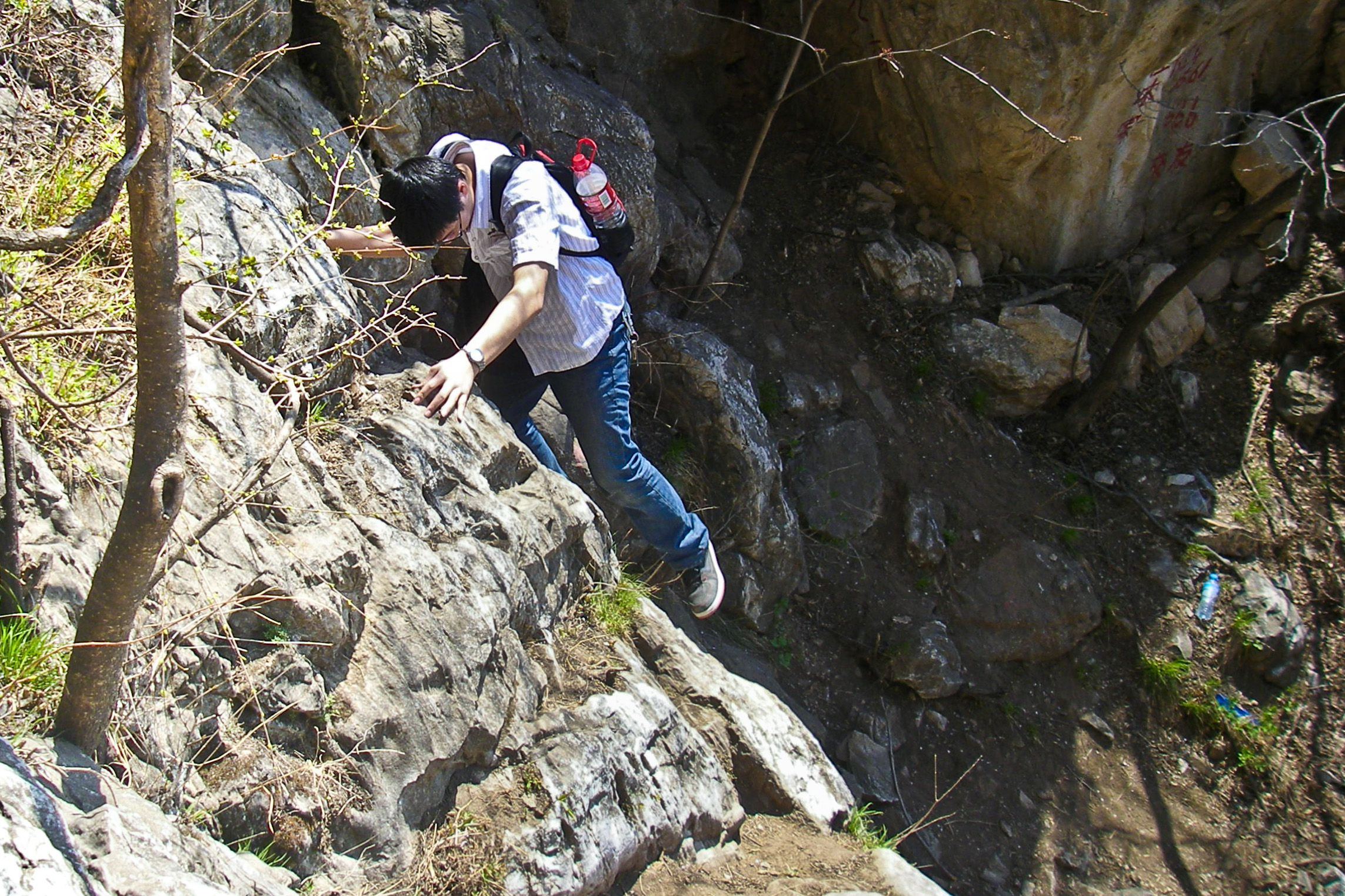 someone climbing a rocky cliff with a bookbag on