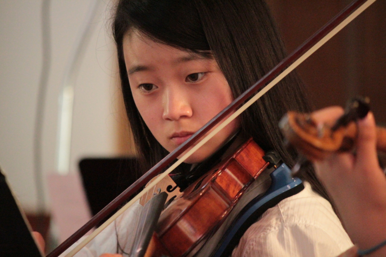 a young asian girl is playing the violin