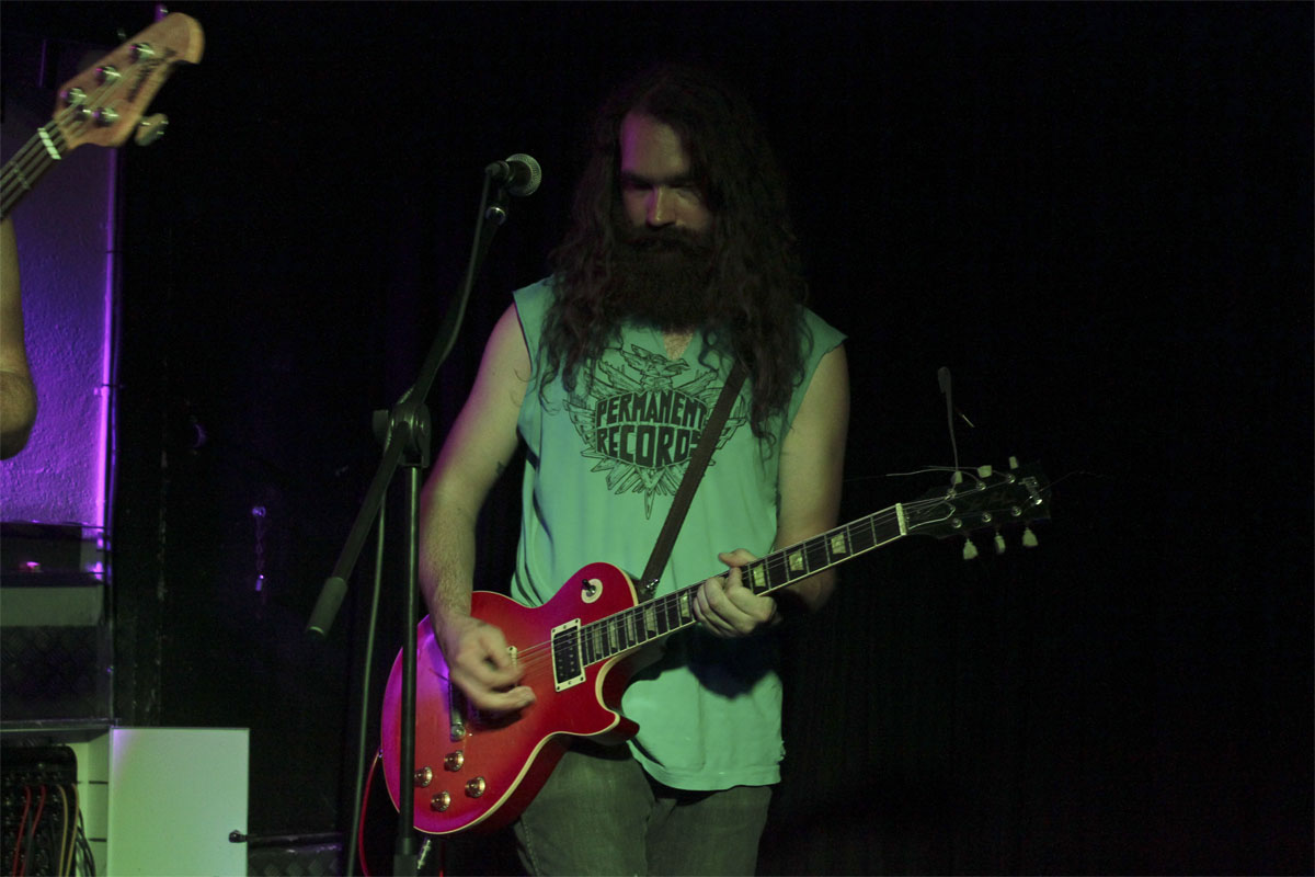 a man with long hair and beard holding a red guitar