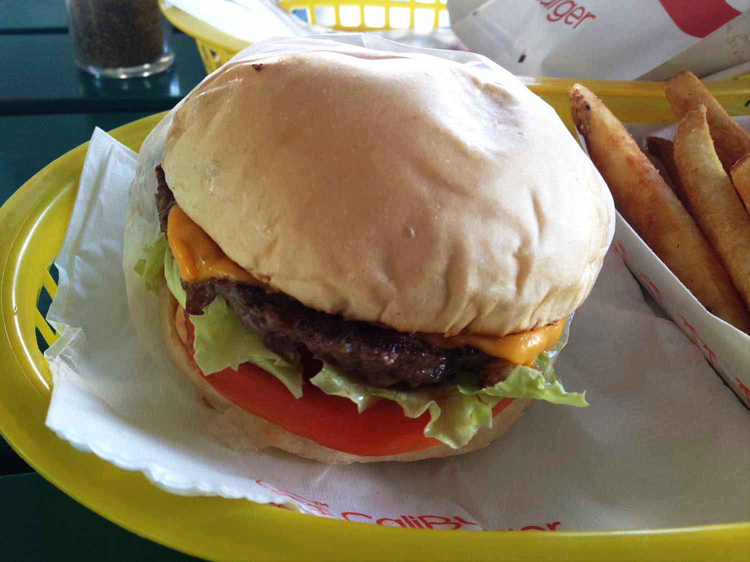 a burger, fries and beverage in a yellow tray