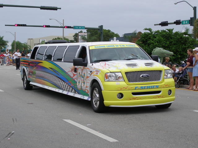 this is a parade with yellow taxi, white suv and decorated with colorful lettering