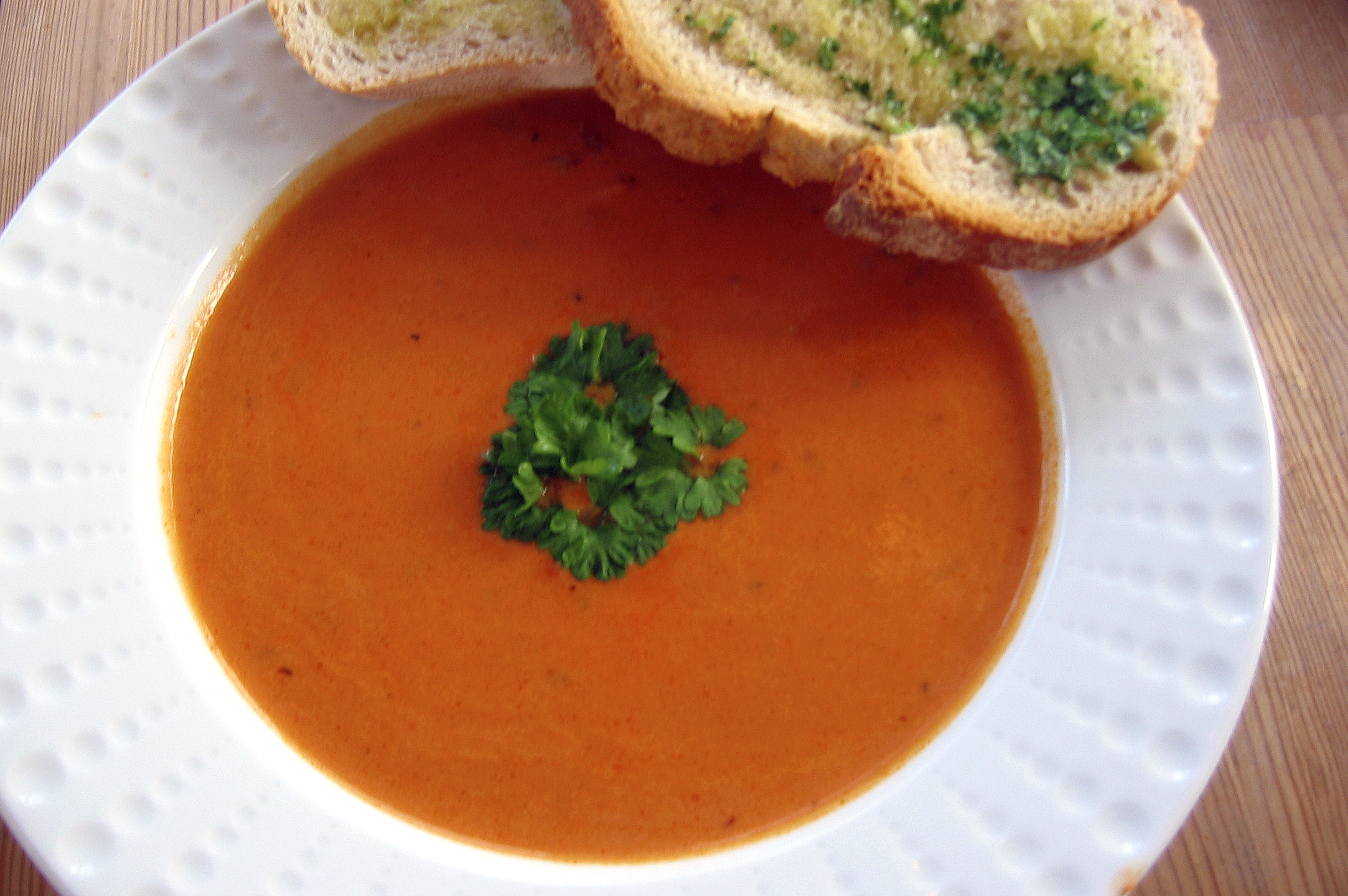 a white plate filled with bread and a bowl of tomato soup