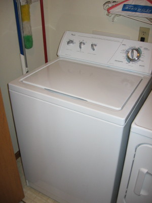 a large white washer in the corner of a laundry room