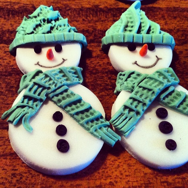 two snowmen wearing hats and scarves decorated on cookies
