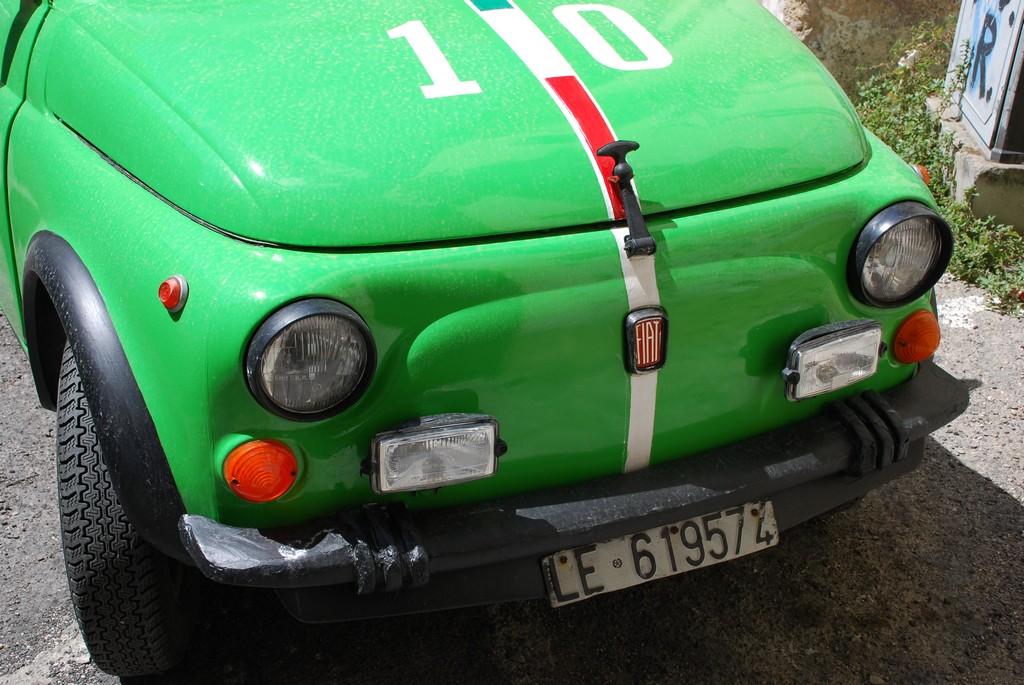 an older green, vintage, compact vehicle with stripes on it