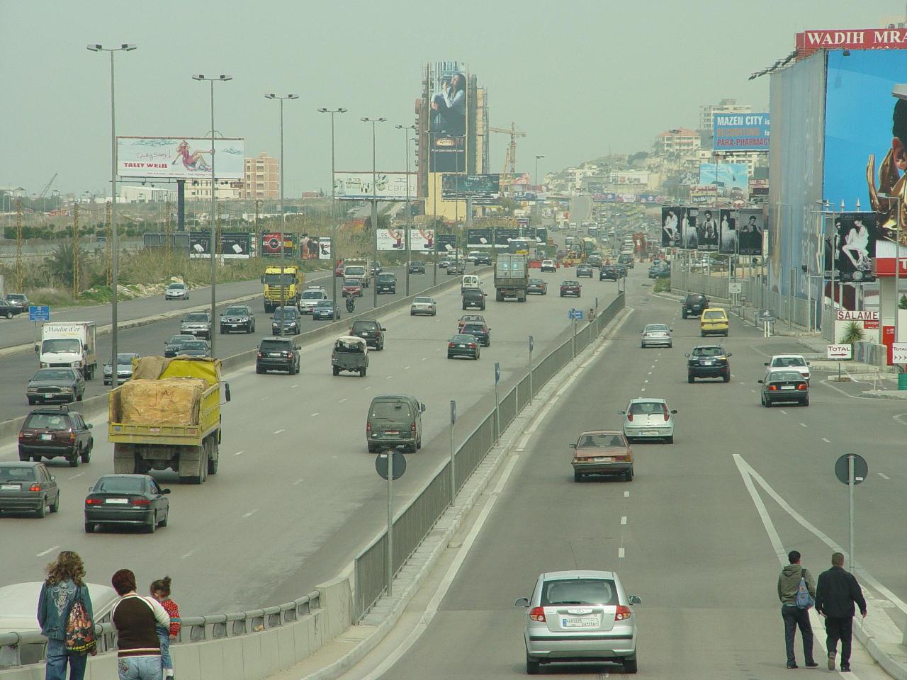 a busy highway with many cars and pedestrians