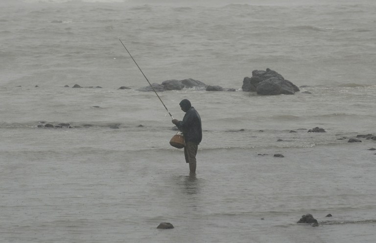 a person is standing on the edge of the water holding a fishing rod