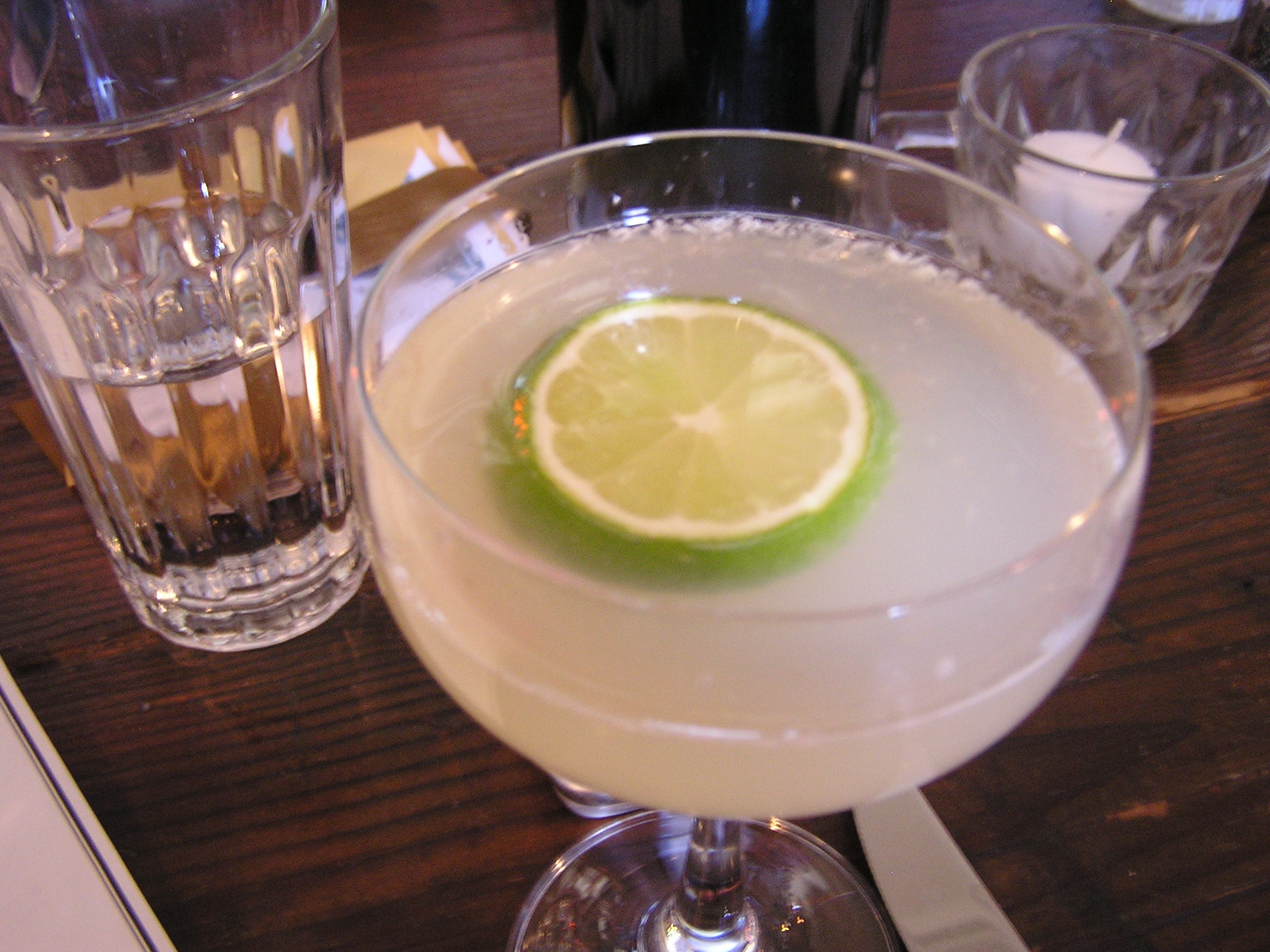 a margarita cocktail with lime garnish and a pitcher of gin