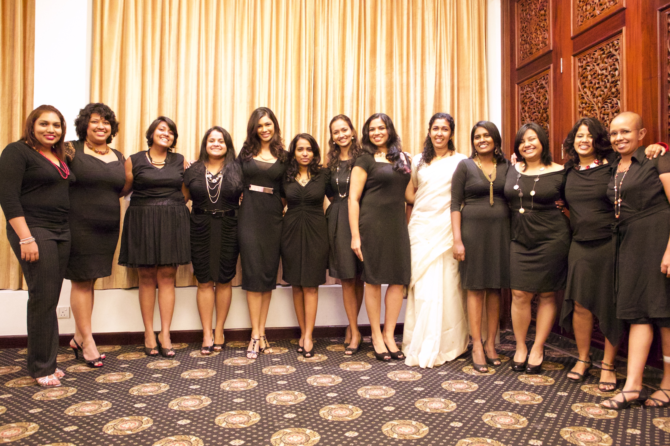 a group of women standing next to each other in dresses