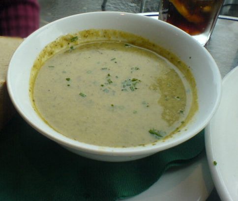 a bowl of soup on a plate next to bread
