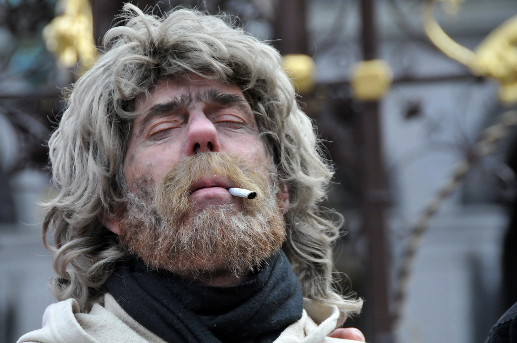 a man with long gray hair and a beard wearing a scarf smoking a cigarette