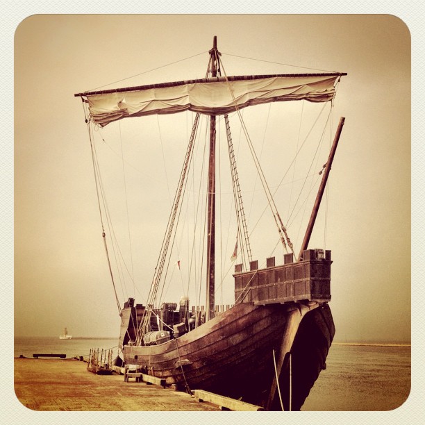 an old ship docked on the shore by the water