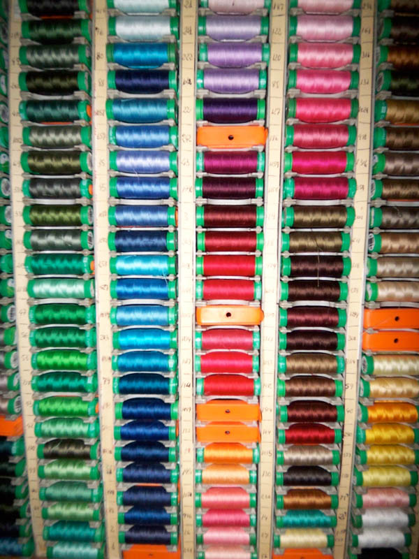 a rack of many spools of thread in a room