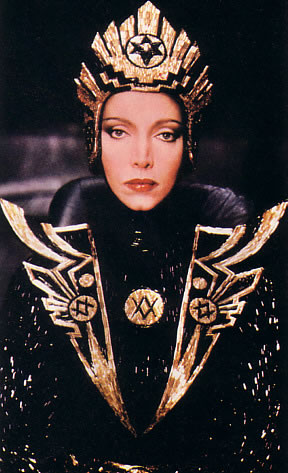 woman with golden costume wearing gold jewelry and black cape
