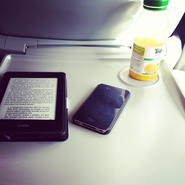 an open smart phone sitting next to a book on top of a white tray