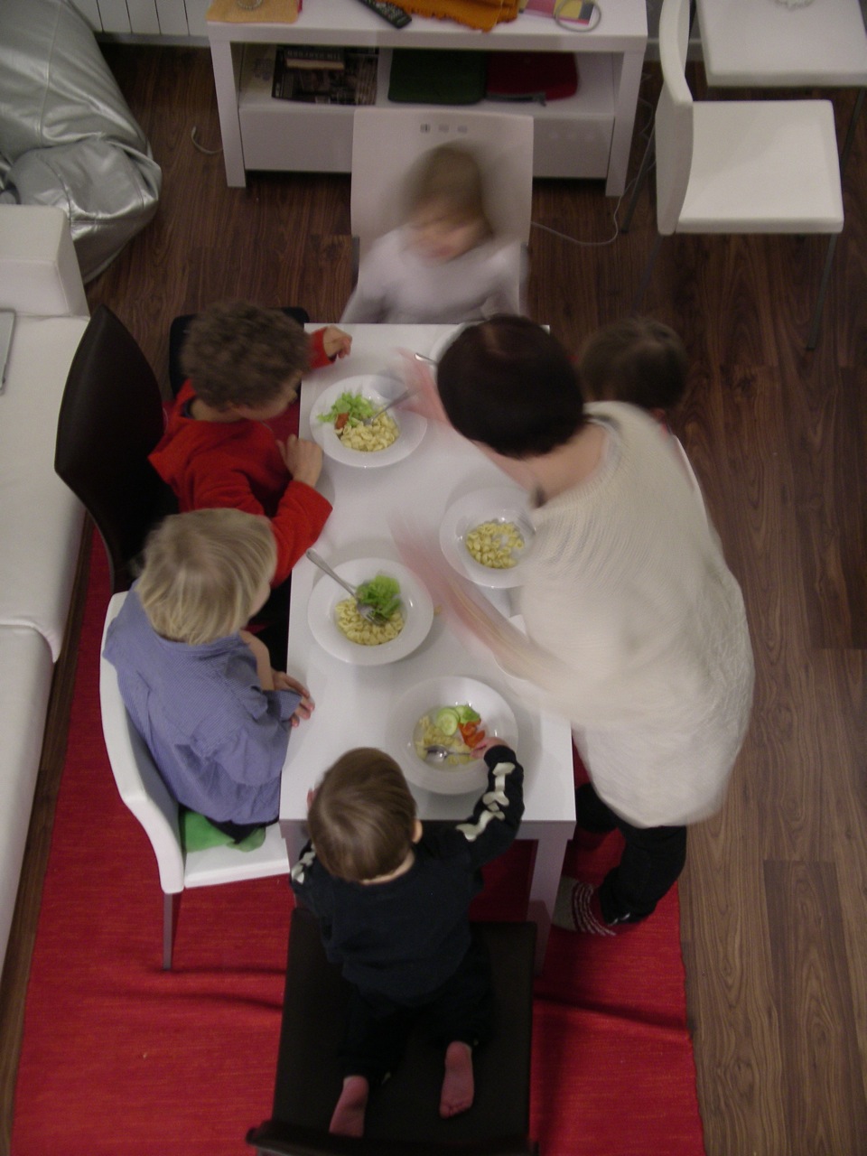 four children sit at a table with a meal on it