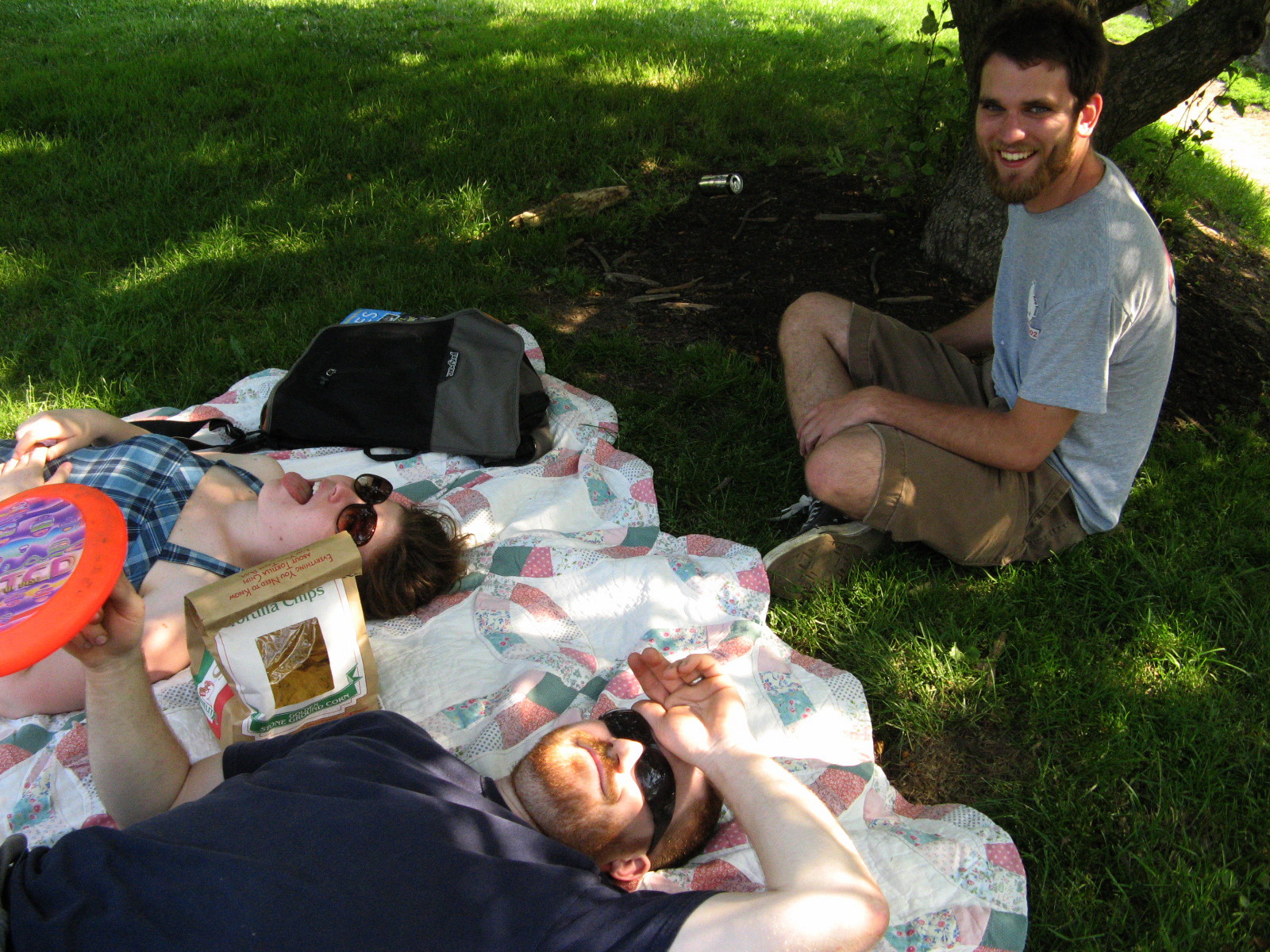 two people laying on a blanket on the grass