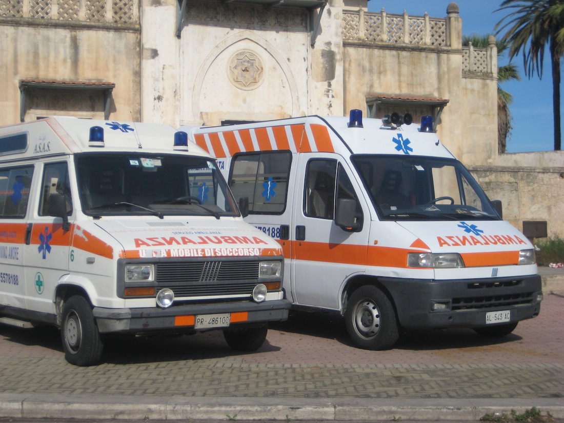 two ambulances are sitting on a street with a building in the background