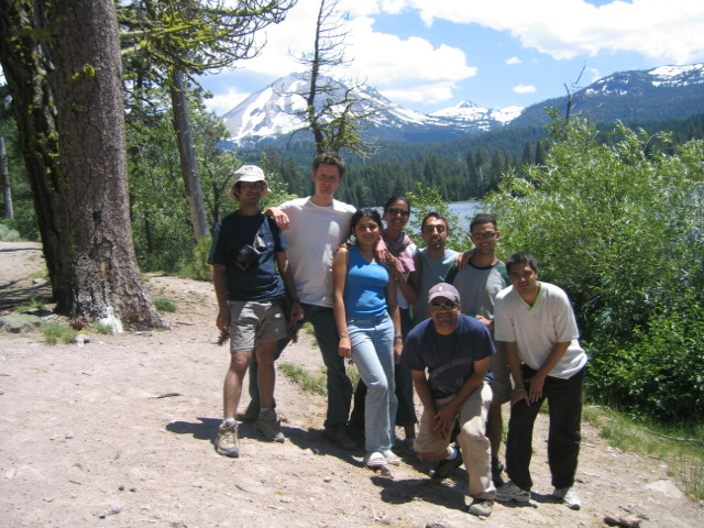 group of people posing in front of mountain and lake